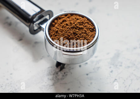 Detailansicht Der portafilter mit gemahlenen Kaffee für die Kaffeemaschine barista auf Marmor tisch Stockfoto