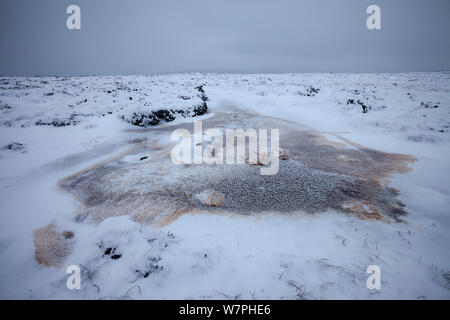 Schnee fleckig Braun von Tannin in gefrorenen moorland Pool. Derwent Kante, Peak District National Park, UK, Januar. Stockfoto