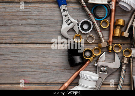 Sanitär Werkzeuge, Rohr und Befestigungen auf einem rustikalen Holzmöbeln Hintergrund. Home Improvement Stockfoto