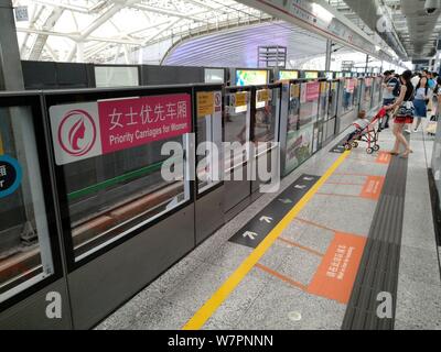 Weibliche Passagiere warten auf einer U-Bahn neben einem Beschilderung von "Priorität Kutschen für Frauen" an der Shenzhen North Station an der Metrolinie 4 in Sie Stockfoto
