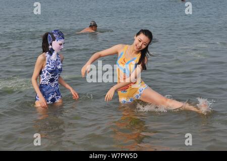 Ein Modell, Links, das Tragen eines facekini Badeanzug mit blau-weißen Porzellan und Stickerei ist dargestellt in einem Beach Resort in Qingdao city, East China Stockfoto