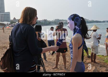 Ein Modell, das Tragen eines facekini Badeanzug mit blau-weißem Porzellan und Stickerei dargestellt an einem Beach Resort in Qingdao Stadt ist, East China Shan Stockfoto