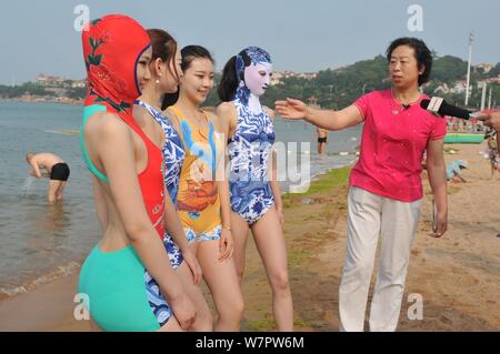 Ein Modell, zweite rechts, trug einen facekini Badeanzug mit blau-weißen Porzellan und Stickerei ist dargestellt in einem Beach Resort in Qingdao Stadt, Ea Stockfoto