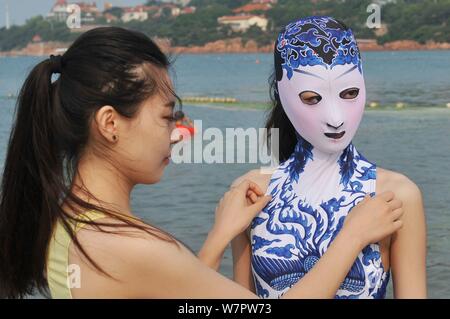 Ein Modell, das Tragen eines facekini Badeanzug mit blau-weißem Porzellan und Stickerei dargestellt an einem Beach Resort in Qingdao Stadt ist, East China Shan Stockfoto