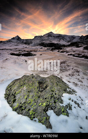 Sonnenuntergang hinter den Bergen mit dem Gefrorenen Lac de Bellecombe im Vordergrund, Nationalpark Vanoise, Savoie, Frankreich, Oktober. Stockfoto