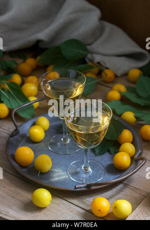 Cherry Plum Likör in kleinen Gläsern und Cherry Plum auf einer hölzernen Hintergrund. Im rustikalen Stil. Stockfoto