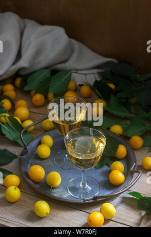 Cherry Plum Likör in kleinen Gläsern und Cherry Plum auf einer hölzernen Hintergrund. Im rustikalen Stil. Stockfoto