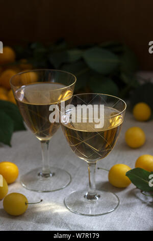Cherry Plum Likör in kleinen Gläsern und Cherry Plum auf einer hölzernen Hintergrund. Im rustikalen Stil. Stockfoto