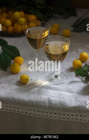 Cherry Plum Likör in kleinen Gläsern und Cherry Plum auf einer hölzernen Hintergrund. Im rustikalen Stil. Stockfoto