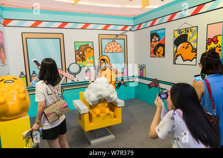 Ein cartoon Enthusiast nimmt ein Foto mit Gudetama, oder faul Ei, von Hello Kitty's Entwickler Sanrio, in Shanghai, China, 19. Juni 2017 erstellt. Die Japa Stockfoto