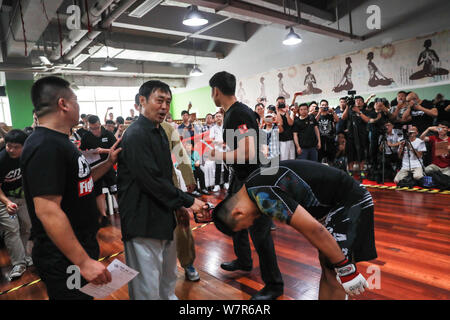 Pensionierte Mixed Martial Arts boxer Xu Xiaodong, rechts, interagiert mit Ma Baoguo, Mitte, ein Meister des Chen Stil Tai Chi, in dem geplanten mass Brawl site Stockfoto