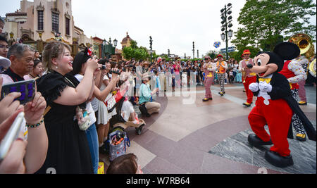 Ein Entertainer gekleidet in einem Mickey Maus Kostüm interagiert mit Touristen während der ersten Jahrestag der zentralen Feier in der Shanghai Disneyland Stockfoto