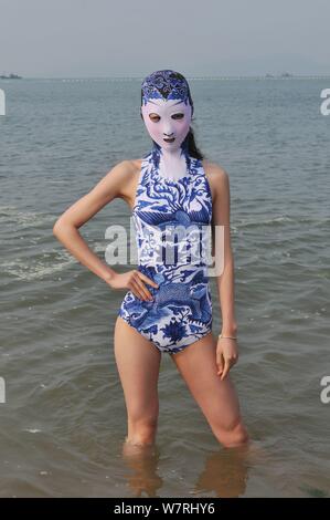 Ein Modell, das Tragen eines facekini Badeanzug mit blau-weißem Porzellan und Stickerei dargestellt an einem Beach Resort in Qingdao Stadt ist, East China Shan Stockfoto