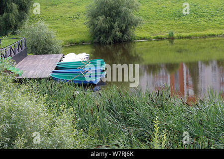 Dock und Boote auf dem See. Leer Fischen Boote auf dem Wasser. Boote für Touristen. Alten hölzernen Boot mit einem Paddel. Stockfoto
