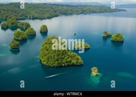 Kalkstein Inseln Kabui Bay, in der Nähe der Östlichen Ende der Passage zwischen Gam und Waigeo. Insel Waigeo oben. Eine lokale Boot ist die Überschrift für die Passage. Raja Ampat Inseln, West Papua, Indonesien. Oktober 2 010 Stockfoto