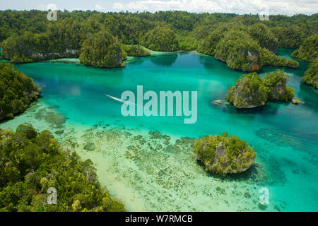 Kalkstein Inseln Kabui Bay, in der Nähe der Östlichen Ende der Passage zwischen Gam und Waigeo. Insel Waigeo oben, mit lokalen Boot überschrift für die Passage. Raja Ampat Inseln, West Papua, Indonesien. Oktober 2010 Stockfoto