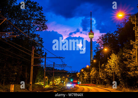 Deutschland, hohe Gebäude der Fernsehturm Stuttgart gefordert Fernsehturm hinter Straßen von Datenverkehr durch die Nacht in der Dämmerung Atmosphäre mit thundery Wolken Stockfoto