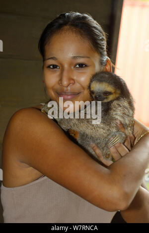 Mädchen, dass junge Blass-throated Trägheit/Aï gebaut (Bradypus tridactylus) Französisch Guyana. Stockfoto