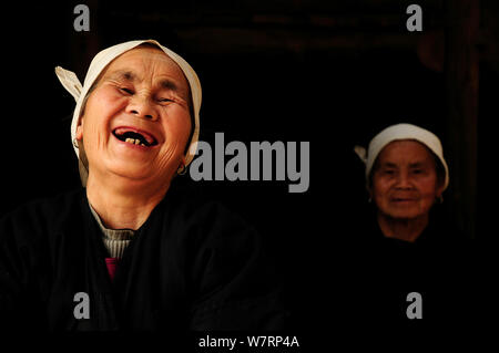 Zwei Dong Frauen, ein Lachen, in einem dunklen Zimmer, Sanjiang Dong Dorf in der Provinz Guangxi, Volksrepublik China. April 2009. Sieger der Fotograf des Jahres, Portrait Kategorie, 4 Pollux Awards, 2012 Stockfoto