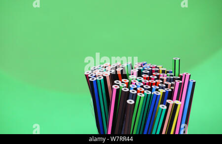 Stand der vielen bunten hellen Zeichenstifte in eine kreisförmige Anordnung mit einem hellgrünen Hintergrund. Stockfoto