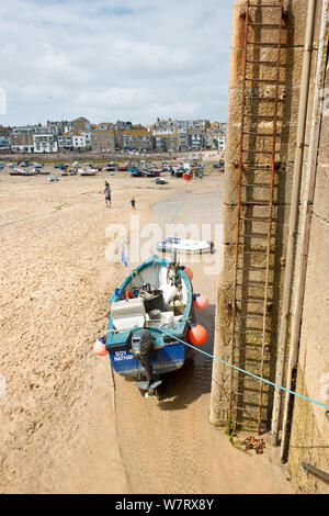 Angeln Boot günstig neben dem Leiter der Hafenmauer und Pier. St Ives, Cornwall, England, Vereinigtes Königreich Stockfoto