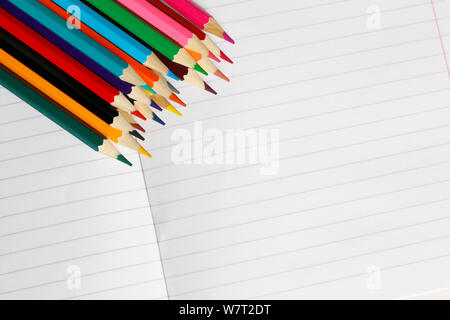 Buntstifte liegen auf einem gestreiften Notebook. Es ist ein Platz für Text. Buntstifte sind in der Nähe gezeigt wird. Bald zur Schule. Zeichnen mit Bleistift in einer no Stockfoto