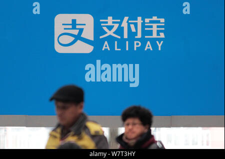 ---- Fußgänger vorbei an einer Anschlagtafel der Alipay in Nanjing, Provinz Jiangsu, China, 26. Dezember 2016. Fahrradfahrer in China sind. Stockfoto