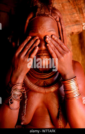 Himba Frau Otjize (eine Mischung aus Butter, Ocker und Asche) auf ihrer Haut, Kaokoland, Namibia, September 2013 anzuwenden. Stockfoto