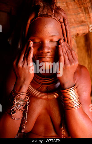 Himba Frau Otjize (eine Mischung aus Butter, Ocker und Asche) auf ihrer Haut, Kaokoland, Namibia, September 2013 anzuwenden. Stockfoto