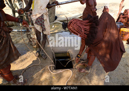 Frau Himba mit einem Seil ziehen Wasser aus einem Brunnen. Kaokoveld, Namibia, September 2013. Stockfoto