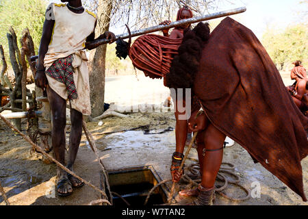 Frau Himba mit einem Seil ziehen Wasser aus einem Brunnen. Kaokoveld, Namibia, September 2013. Stockfoto