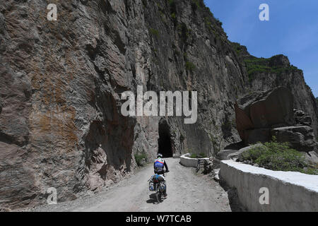 Ein Radfahrer fährt auf der Straße von den lokalen Dorfbewohnern geschnitzt auf der Kante einer Klippe auf taihang Mountains im Pingshun Hongtiguan Dorf, Grafschaft, Changzhi cit Stockfoto