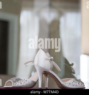 Bräute Schuhe mit Reflexion der Kleid im Hintergrund an Ihrem Hochzeitstag, Braut prep Fotografie Stockfoto