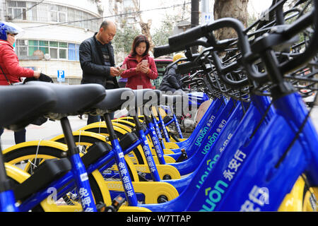 ---- Einheimische verwenden Sie die App der Chinesischen bike-sharing service Youon auf ihren Smartphones Fahrräder in Xiangyang Stadt zu mieten, der Central China Hubei provin Stockfoto