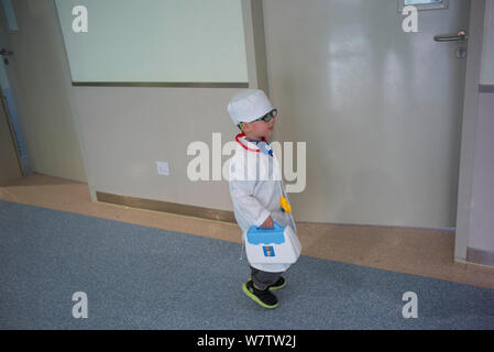 Drei-jährige Chinese Chen Chen trägt ein weißes Kleid mit einem Medical Kit wird dargestellt, wie er Checkup Patienten gibt in eine Kinderklinik in Wu Stockfoto