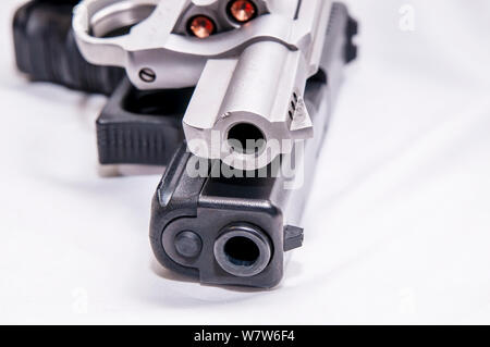 Zwei Pistolen, ein silberner snub Spitzzange 357 Magnum Revolver und ein schwarzes 9-mm-Pistole auf weißem Hintergrund Stockfoto