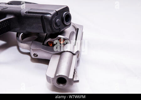 Zwei Pistolen, ein silberner snub Spitzzange 357 Magnum Revolver und ein schwarzes 9-mm-Pistole auf weißem Hintergrund Stockfoto