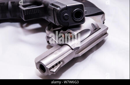 Zwei Pistolen, ein silberner snub Spitzzange 357 Magnum Revolver und ein schwarzes 9-mm-Pistole auf weißem Hintergrund Stockfoto