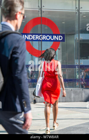 Ein Mann und eine Frau auf ihren morgendlichen Fahrt am Eingang zur U-Bahnstation Victoria, Central London. Stockfoto