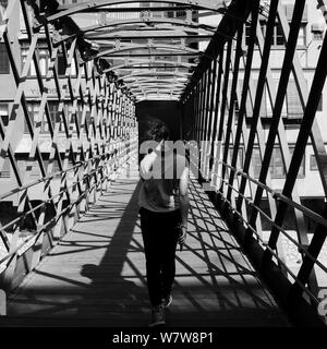 Rückansicht eines jungen Mädchens mit flatternden Haare zu Fuß über die Pont de les Peixateries Velles, durch G. Eiffel in Girona, Katalonien, Spanien Stockfoto