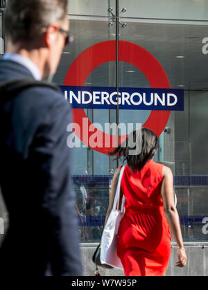 Ein Mann und eine Frau auf ihren morgendlichen Fahrt am Eingang zur U-Bahnstation Victoria, Central London. Stockfoto