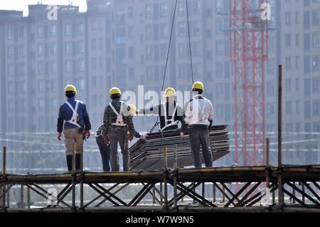 ------ Chinesische Wanderarbeiter ein hohes Gebäude auf der Baustelle eine Wohn- Projekt in Nanjing city konstruieren, e Stockfoto