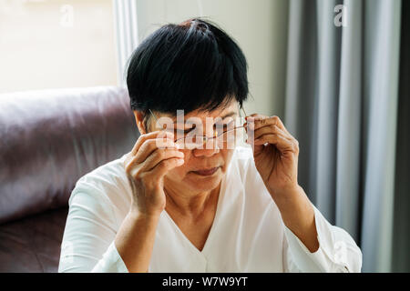 Porträt einer alten Frau, die ihre Brille Stockfoto
