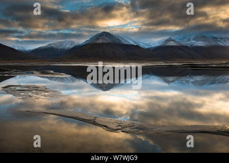 Berge mit Gipfeln in einer leichten Schicht Schnee bedeckt in Wasser, Adventdalen, Spitzbergen, Svalbard, Norwegen, September 2013. Stockfoto