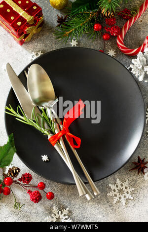 Weihnachten Hintergrund. Weihnachten Dekoration Tisch. Festliches schwarz Teller und Besteck mit weihnachtlichen Dekor auf Retro festlichen Tisch. Stockfoto