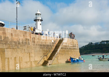 Kleines Fischerboot neben St Ives Pier und den Leuchtturm. St Ives, Cornwall, England, Vereinigtes Königreich Stockfoto