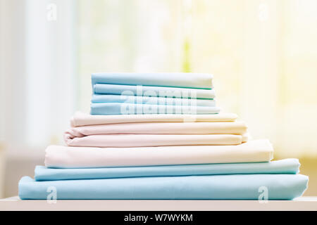 Closeup Stack von blauen und weißen sauberes Bettzeug auf dem Tisch. Unscharfer Hintergrund. Stockfoto