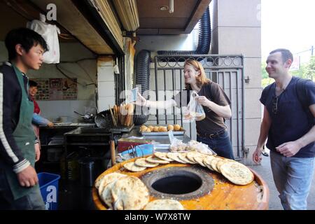 Australische Mann Tim Clancy nimmt seinen amerikanischen Freund für ihr Frühstück durch mobile Zahlung an einem strassenrand in Hangzhou city Stall zu bezahlen, East China Stockfoto