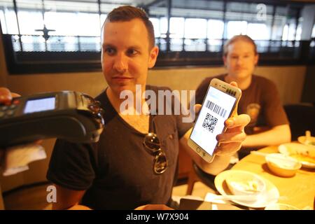 Australische Mann Tim Clancy nimmt seinen amerikanischen Freund für Ihre Mahlzeiten durch mobile Payment in einem Restaurant in Hangzhou city zu bezahlen, der East China Zheji Stockfoto