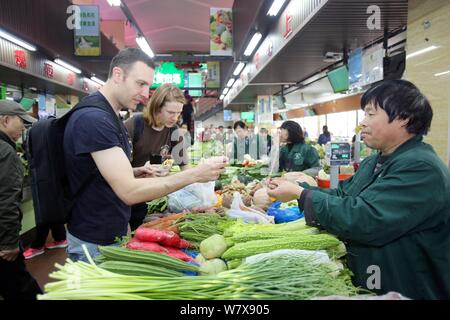 Australische Mann Tim Clancy nimmt seinen amerikanischen Freund für Gemüse durch mobile Payment an einem Markt in Hangzhou city zu bezahlen, der East China Zhejiang p Stockfoto